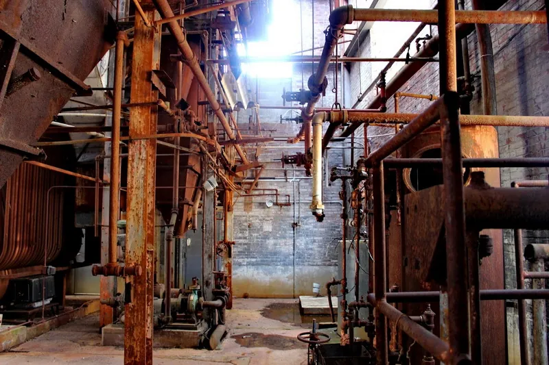 Rusting pipework inside an abandoned industrial building, photographed by Tom Atkins